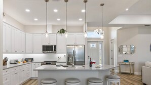 A modern kitchen with white cabinets, stainless steel appliances, and a central island with bar stools.
