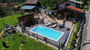 Una piscina con muelle de madera, sillas de descanso y una hamaca.