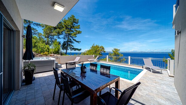 A poolside area with a table and chairs, a hot tub, and a view of the sea. - Villa Antonia by Villas Guide (Smokvica)