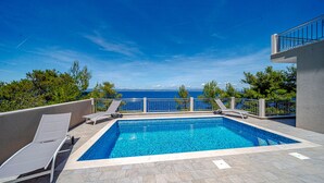 A rectangular swimming pool with a clear view of the sea and mountains in the background. - Villa Antonia by Villas Guide (Smokvica)