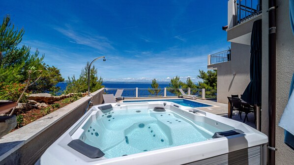 Un jacuzzi con vistas al mar, mobiliario exterior y un edificio con balcón.