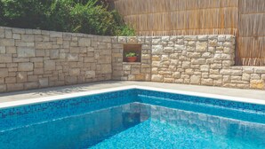 Una piscina con paredes de piedra y una planta en maceta.