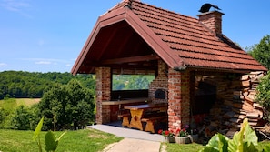 Un bâtiment rustique en pierre, doté d’un toit en pente, d’une cheminée en briques et d’un banc en bois.