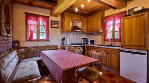 Une cuisine chaleureuse avec des meubles en bois, une table à manger recouverte d’une nappe à carreaux et un four encastré.