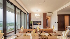 Un comedor con una mesa preparada para cuatro, una figura decorativa de ciervo y vistas de un río a través de amplios ventanales.
