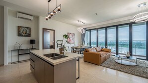 Una cocina moderna con una isla central, un comedor con vistas y un salón con un amplio ventanal que da a una masa de agua.