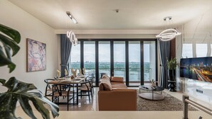 Una sala de estar moderna con comedor, ventanas amplias y vistas a un paisaje urbano.