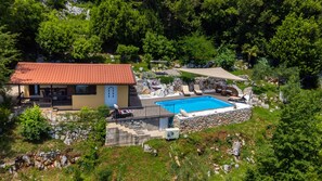 Ein Haus mit Swimmingpool, Sitzgelegenheiten im Freien und einer Steinmauer.