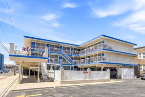 A multi-story hotel with balconies, a covered entrance, and a private parking area.