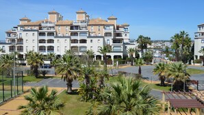 Un hotel de varios pisos con balcones, estacionamiento y palmeras.