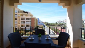 Un balcón con una mesa y sillas, con vista a una zona residencial con edificios de varios pisos.