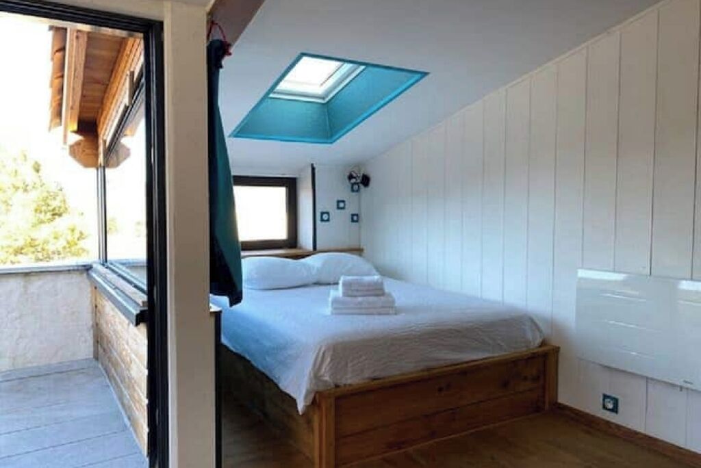 Ein Schlafzimmer mit Oberlicht, einem hölzernen Bett, einem Fenster und einem Balkon.