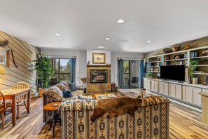 A cozy living room with a fireplace, a television, and a bookshelf.