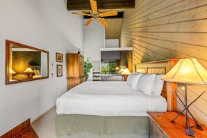 A bedroom with a large bed, wooden ceiling, and a view of a balcony.