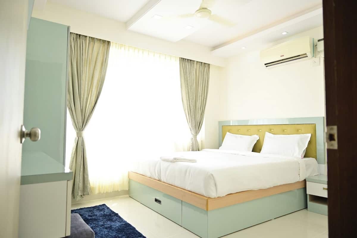 A bedroom with a bed, curtains, an air conditioning unit, and a ceiling fan.