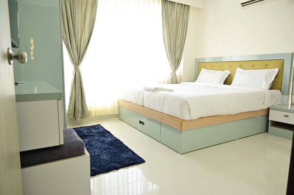 Une chambre moderne avec un lit, des tables de chevet, une armoire et un tapis bleu.