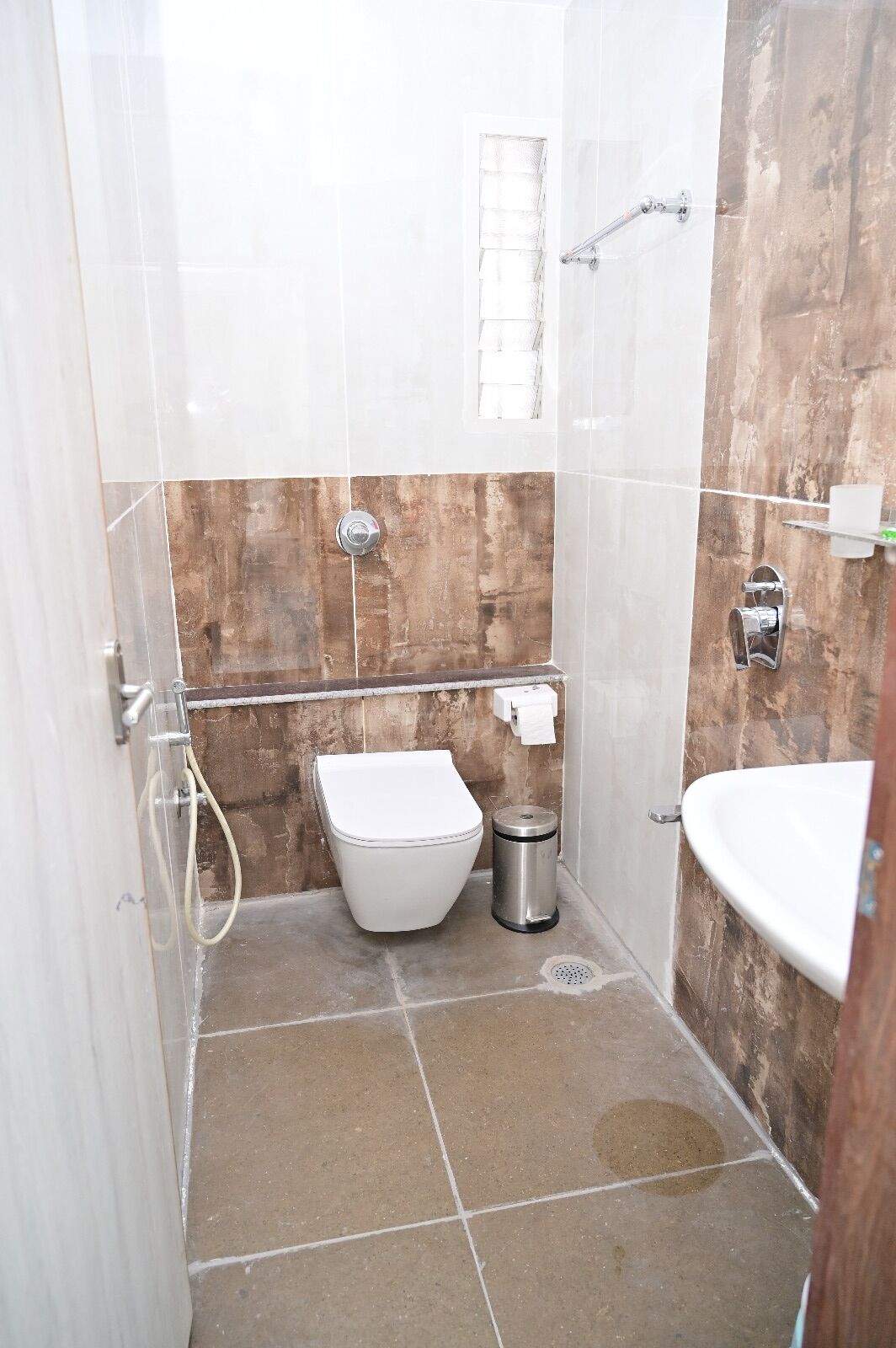 A small bathroom with a toilet, a trash can, and a sink.