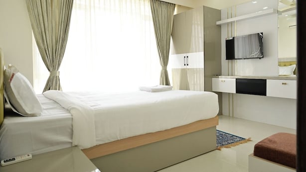 Una habitación de hotel moderna con una cama grande, televisor, escritorio y armario.