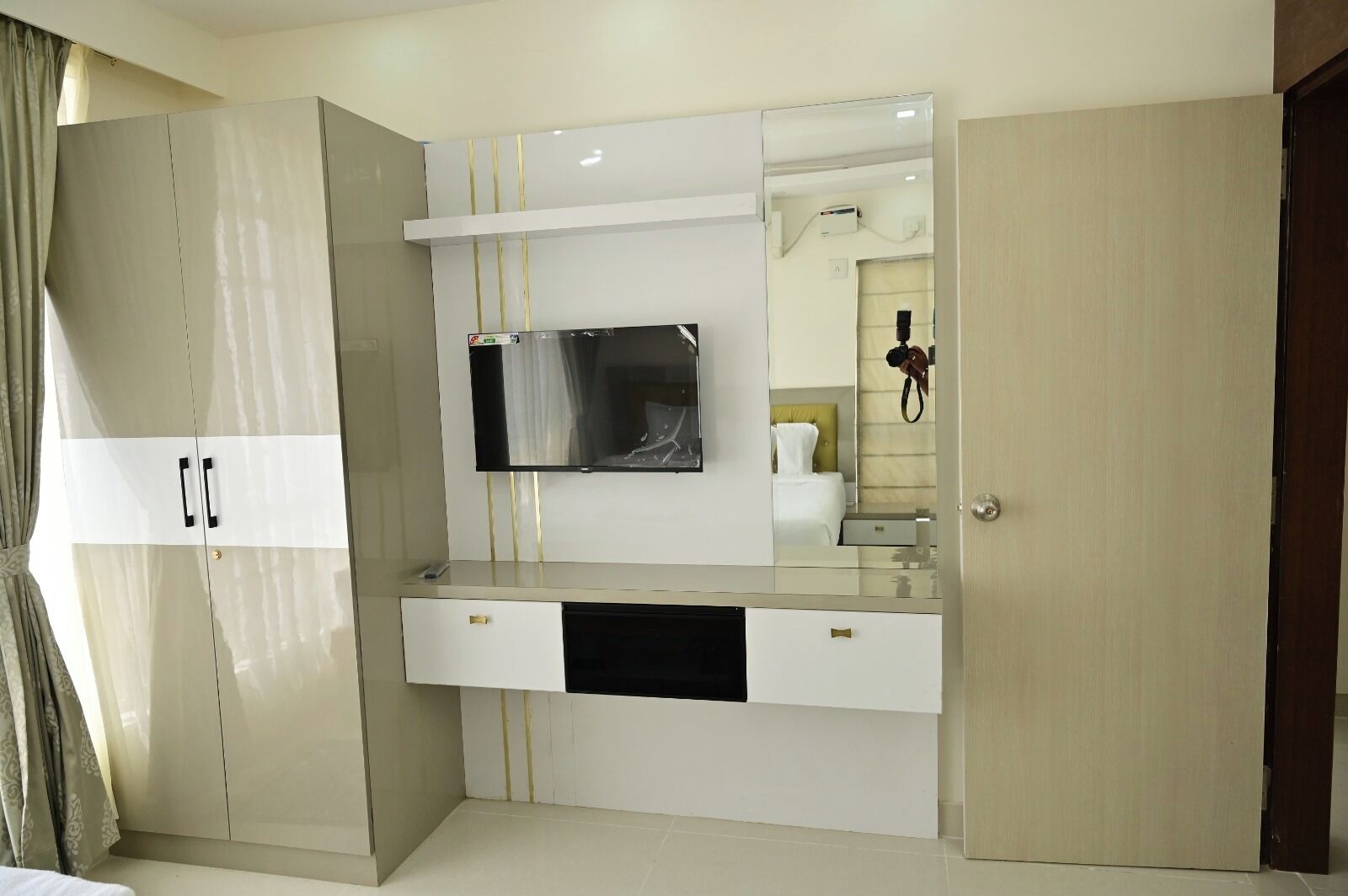 Une chambre moderne dotée d’une grande armoire, d’un téléviseur encastré et d’un miroir.