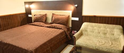 A hotel room with a large bed, a chair, and a small table.