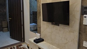 Una sala moderna con un televisor de pantalla plana montado en una pared de mármol, un banco empotrado con cajones e iluminación empotrada en el techo.