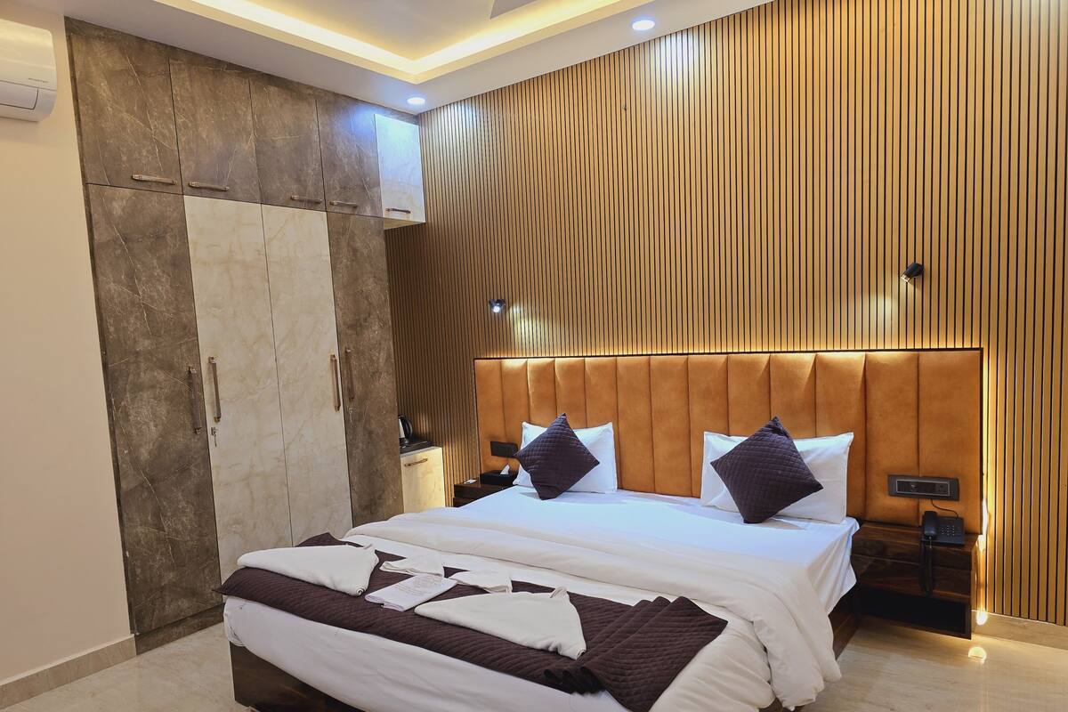 Ein modernes Hotelzimmer mit einem großen Bett, Holzwandverkleidung, einem Marmorboden und einem integrierten Schreibtisch mit Telefon.