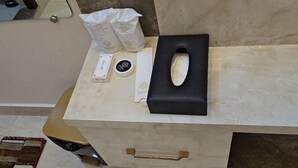 Un mostrador de recepción de mármol con una carpeta negra, una caja de pañuelos y un pequeño recipiente.