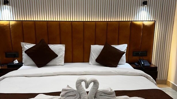 Habitación de hotel con una cama grande, dos mesitas de noche, un cabecero y una pared con líneas verticales.