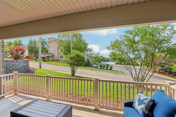 A balcony with a view of a road, trees, and a building across the street.