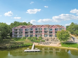A multi-story hotel with a red and white facade, located near a body of water with a dock. - Bushwood at Delton Grand (Wisconsin Dells)