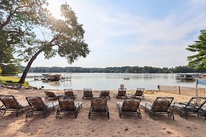 A lakeside seating area with metal chairs and tables, a dock, and a sign for Lighthouse Cove.