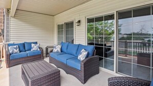 A covered porch with two blue sofas and wicker furniture. - Bushwood at Delton Grand (Wisconsin Dells)