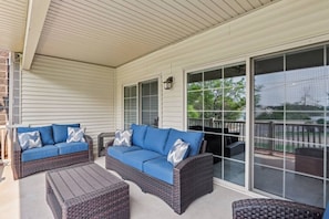 A covered porch with two blue sofas and wicker furniture. - Bushwood at Delton Grand (Wisconsin Dells)