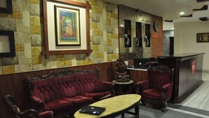 En lobby med en rød sofa, et træbord, en statue og en receptionsdisk.