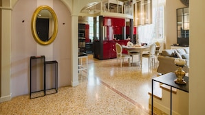 A spacious living area with a kitchen in the background, a round mirror, and a dining table with chairs.