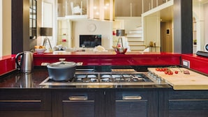 A modern kitchen with a red accent wall, a gas stove, and a large window overlooking the living area.