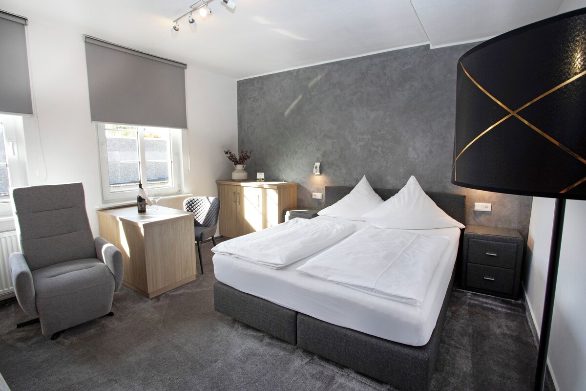 Une chambre d’hôtel moderne avec un grand lit, un bureau, une chaise et une lampe.