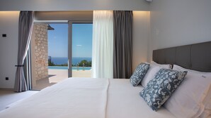 Un hotel moderno con una cama grande, vistas al mar y una pared de piedra.