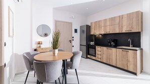 Une cuisine moderne avec des meubles en bois, un plan de travail noir et un four encastré. On y trouve également un coin repas avec une table ronde et des chaises grises.