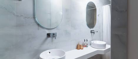 Un baño moderno con dos espejos redondos, un lavabo blanco y una zona de ducha.