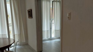 A room with a wooden dining table and chairs, a sliding glass door leading to a balcony, and a wall-mounted air conditioning unit.