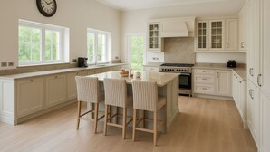 Une cuisine moderne dotée d’un îlot central, de meubles blancs et d’une grande fenêtre.