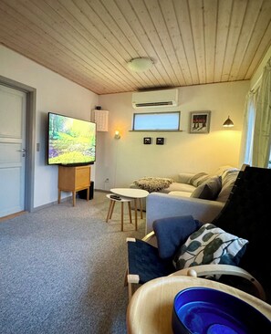Een gezellige woonkamer met een televisie, een tafeltje en een bank.