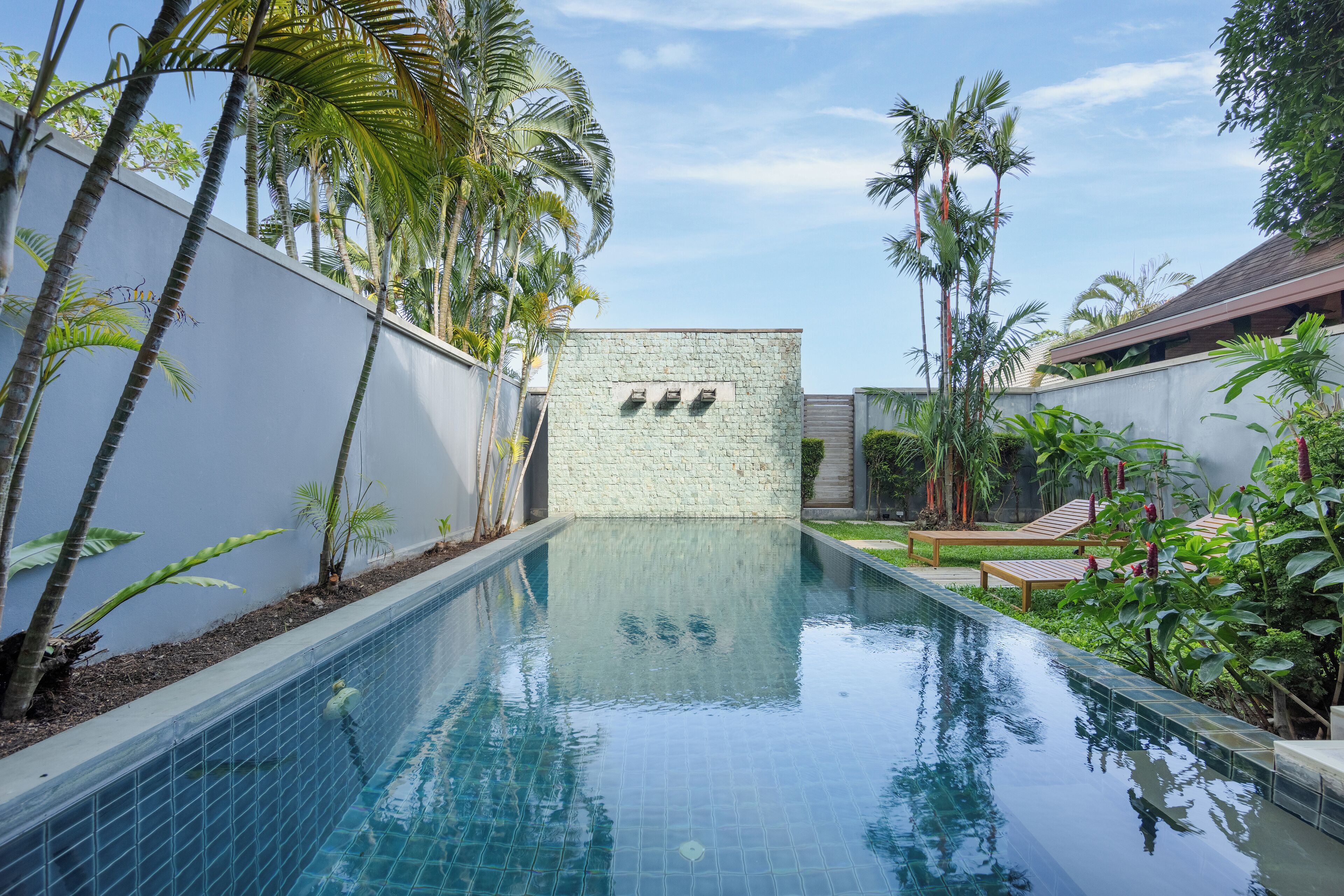 A swimming pool with tiled walls and a stone wall in the background.