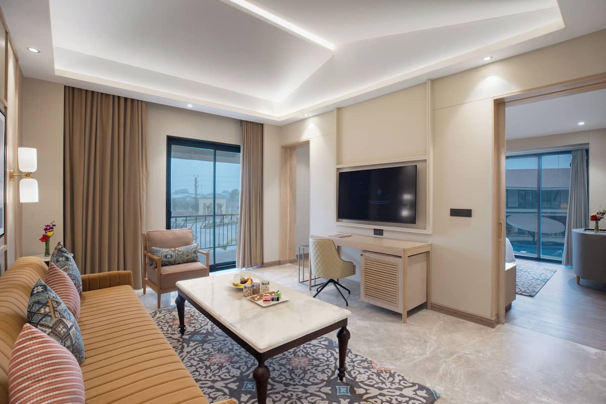 Een moderne hotelkamer met een bank, een eettafel, een televisie en een balkon met uitzicht.