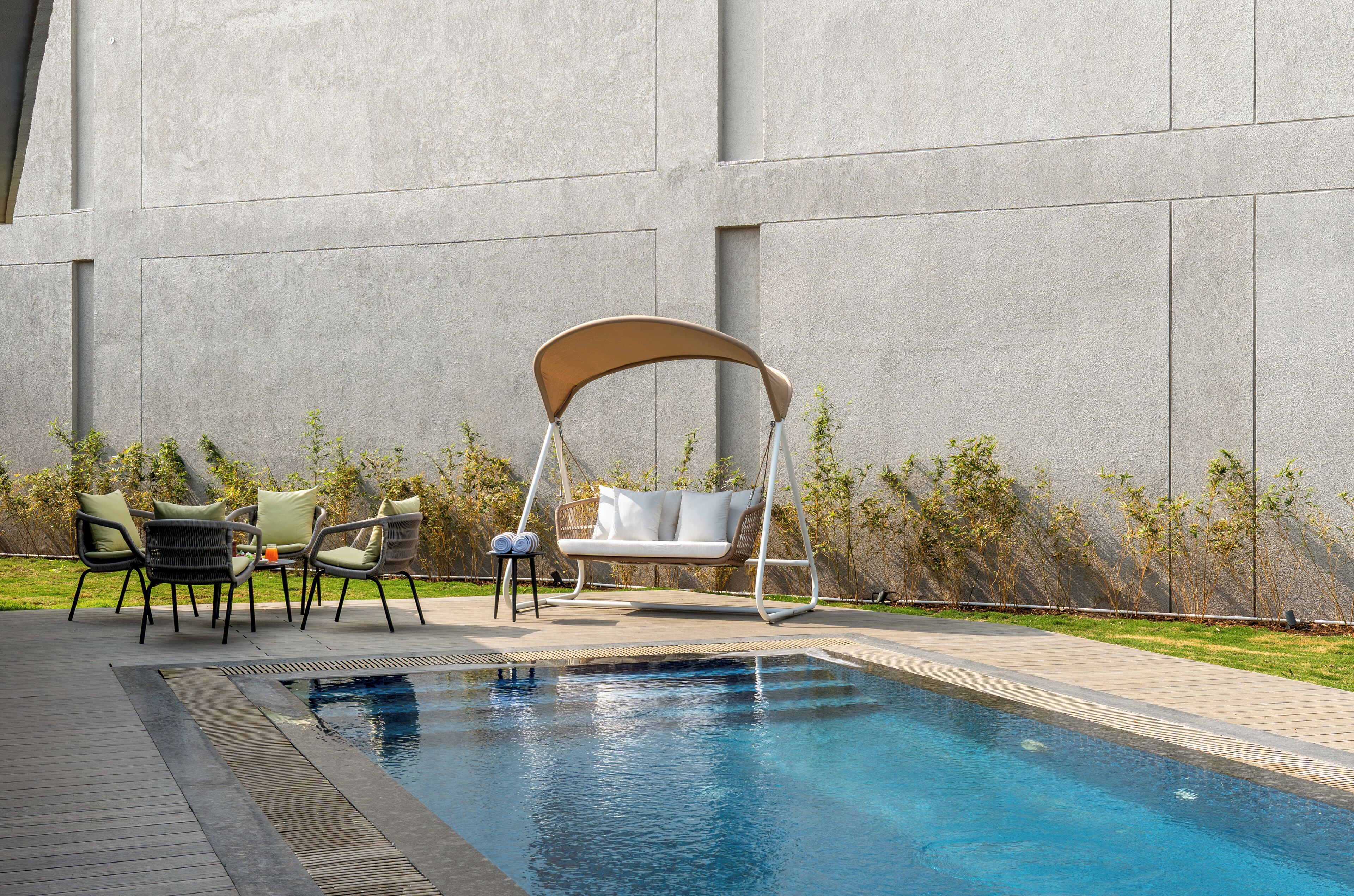 Una piscina con una sedia a dondolo, due poltrone da relax e un tavolino.