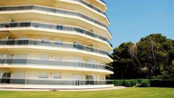 Un edificio de varios pisos con balcones, techo plano y un césped bien cuidado.