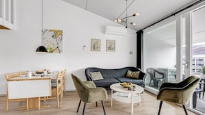 Ein modernes Wohnzimmer mit einer Couch, Sesseln, einem Esstisch und Kunstwerken an den Wänden.