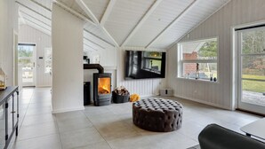 Ein modernes Interieur mit Kaminofen, Flachbildfernseher und großem Fenster mit Blick ins Freie.