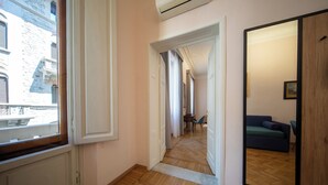 A hallway with a wooden herringbone floor, a large mirror, and a view of a cityscape through a window. - Mantellate 9 (Florence)